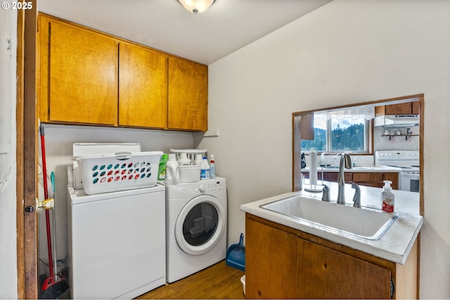 washroom featuring washing machine and dryer, wood finished floors, a sink, and cabinet space