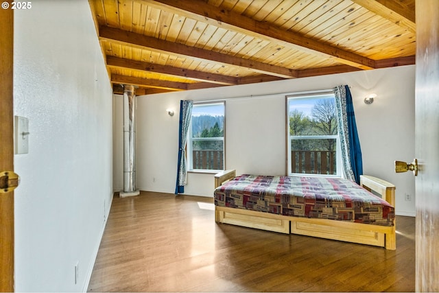 bedroom featuring beamed ceiling, wood finished floors, and wooden ceiling