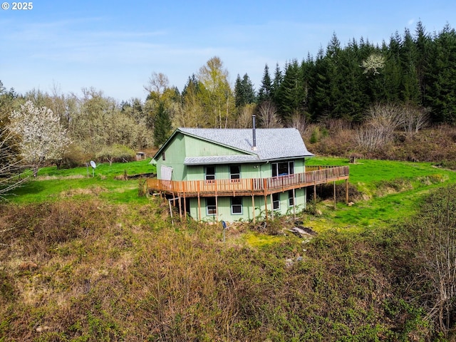 rear view of house featuring a wooden deck and a view of trees
