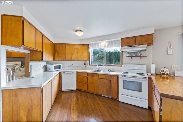 kitchen featuring brown cabinets, under cabinet range hood, a sink, and white appliances