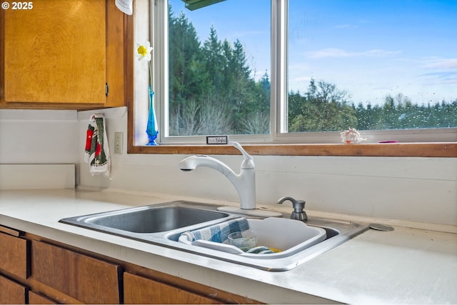 details with light countertops, brown cabinetry, and a sink