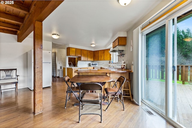 dining space featuring visible vents, light wood-style flooring, and a healthy amount of sunlight