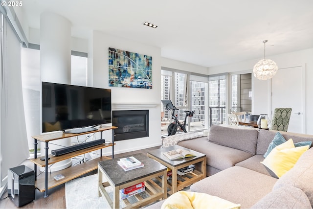 1075 NW Northrup St Unit 814, Portland, OR 97209 - living room with baseboards, a glass covered fireplace, wood finished floors, and a chandelier