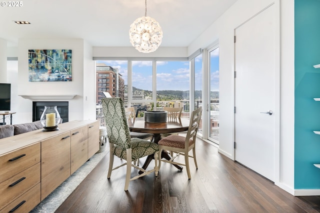 1075 NW Northrup St Unit 814, Portland, OR 97209 - dining area featuring a glass covered fireplace, baseboards, dark wood-style floors, and a notable chandelier