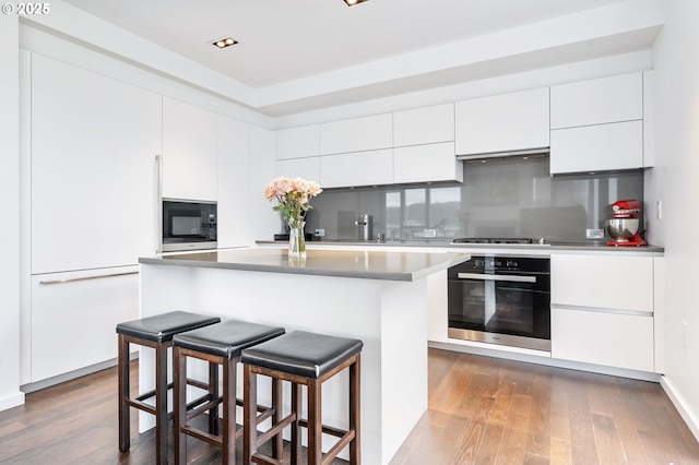 1075 NW Northrup St Unit 814, Portland, OR 97209 - kitchen featuring a breakfast bar area, wall oven, black microwave, and modern cabinets