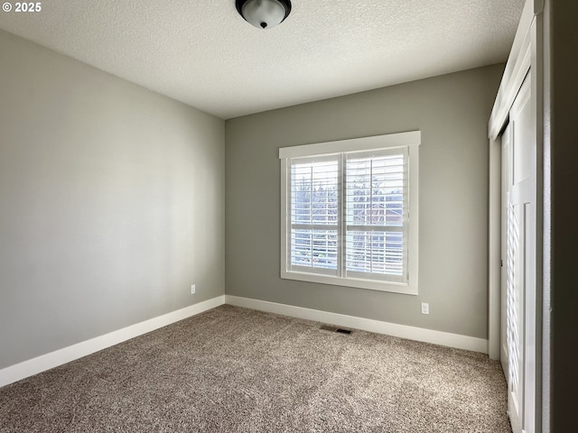 unfurnished room with a textured ceiling and carpet flooring