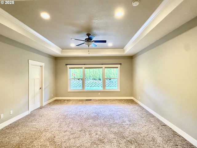 spare room with ceiling fan, a tray ceiling, and carpet flooring