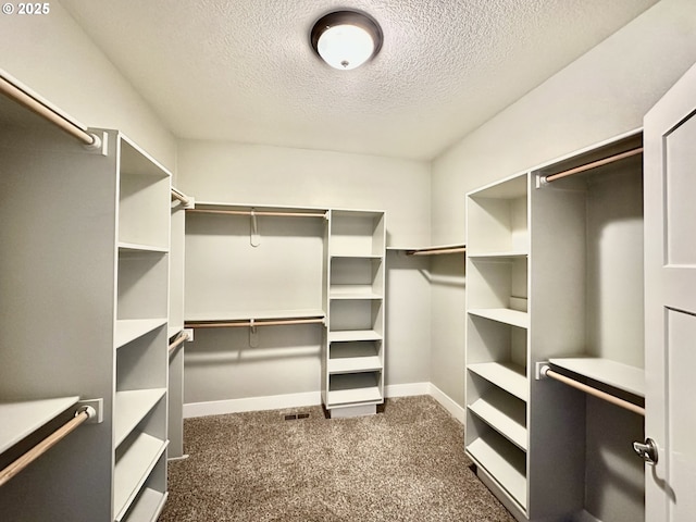 walk in closet with dark carpet