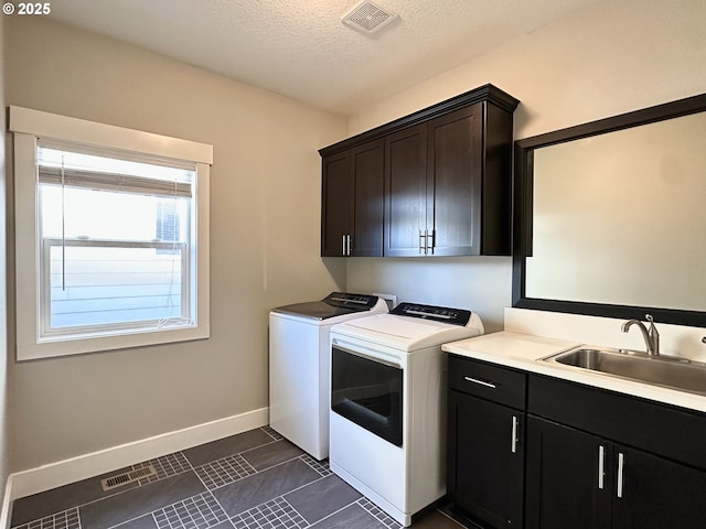 laundry area featuring washing machine and dryer, a textured ceiling, cabinets, and sink