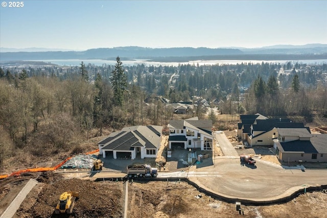 aerial view featuring a wooded view and a water and mountain view