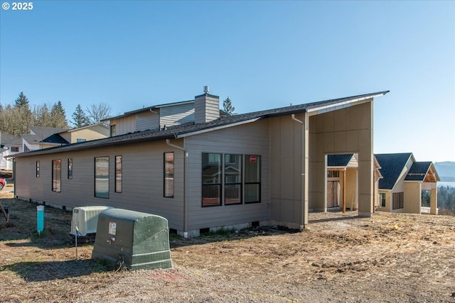 back of property featuring a chimney and central AC