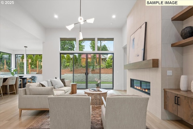 living area featuring recessed lighting, light wood-type flooring, and a glass covered fireplace