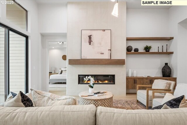 kitchen with wall chimney range hood, white cabinetry, a center island with sink, and refrigerator