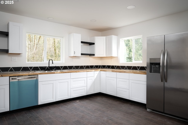 kitchen featuring open shelves, white cabinets, stainless steel refrigerator with ice dispenser, dishwasher, and a sink