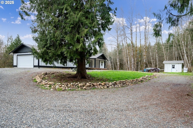 view of front of home with a front yard, driveway, an outdoor structure, and an attached garage