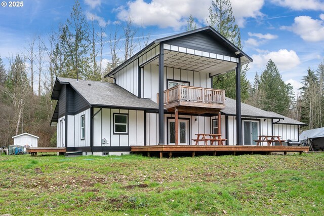 back of property with board and batten siding, a wooden deck, a shed, a lawn, and a balcony