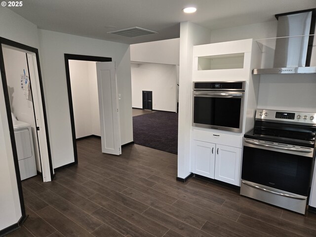 kitchen with visible vents, white cabinets, dark wood-style flooring, wall chimney range hood, and appliances with stainless steel finishes