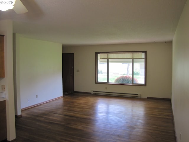 spare room featuring dark hardwood / wood-style floors, baseboard heating, and ceiling fan