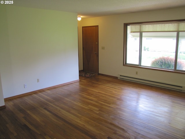 empty room featuring dark hardwood / wood-style floors and baseboard heating