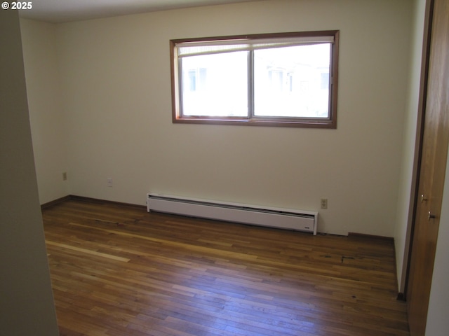 spare room with dark hardwood / wood-style flooring and a baseboard radiator