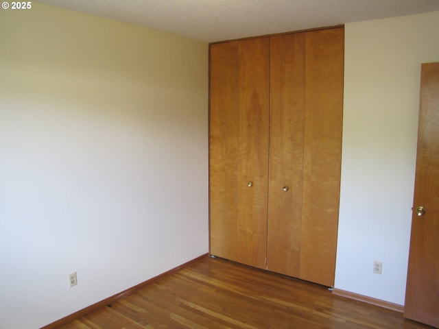 unfurnished bedroom featuring a textured ceiling, hardwood / wood-style flooring, and a closet