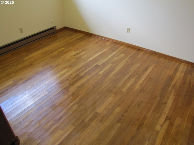 unfurnished room featuring light wood-type flooring and a baseboard heating unit