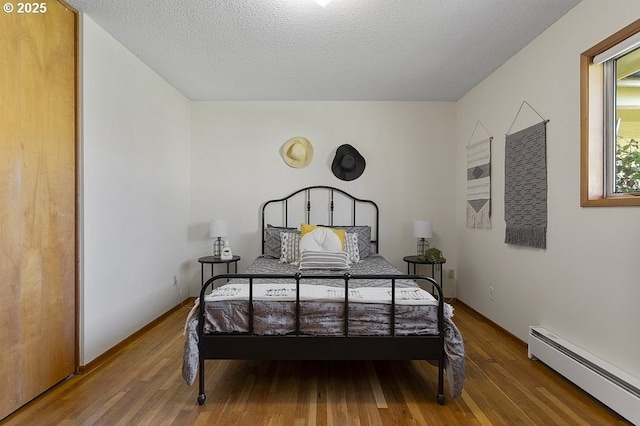 12395 SE Main St, Portland, OR 97233 - bedroom featuring a baseboard radiator, wood finished floors, and a textured ceiling