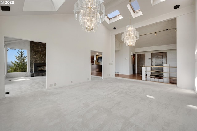 unfurnished living room with a chandelier, a skylight, a fireplace, a towering ceiling, and carpet floors