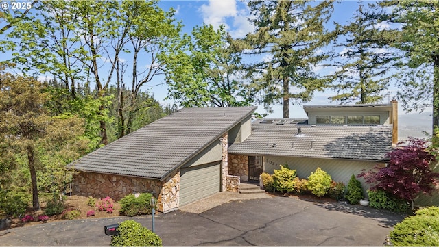 view of property exterior with stone siding, a tiled roof, driveway, and a garage
