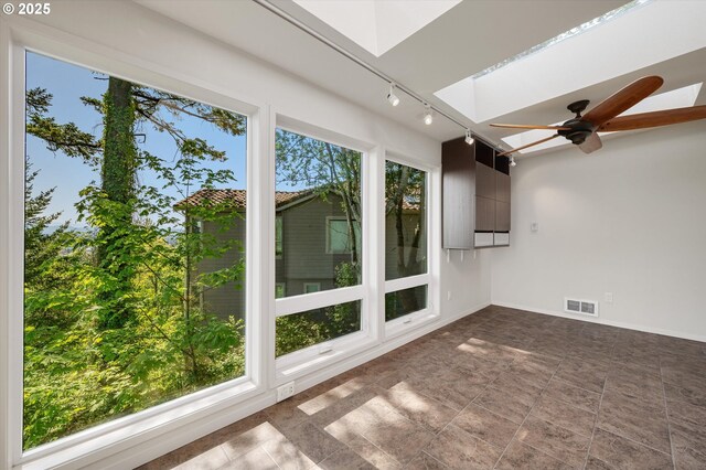 unfurnished sunroom with track lighting and a skylight