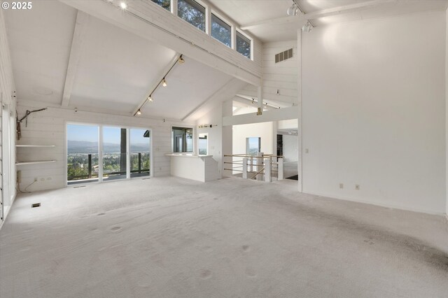 unfurnished living room featuring carpet flooring, high vaulted ceiling, beam ceiling, and track lighting