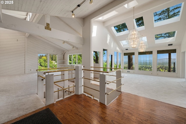 hall featuring a skylight, an upstairs landing, high vaulted ceiling, wood finished floors, and beamed ceiling