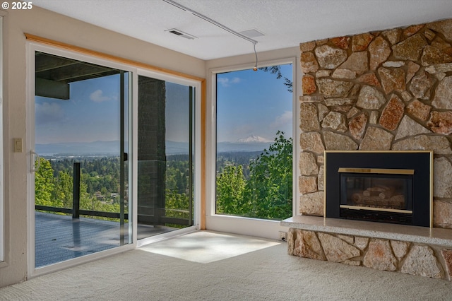 unfurnished living room with carpet flooring, healthy amount of natural light, a fireplace, and a textured ceiling
