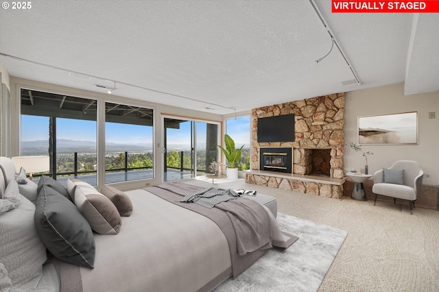 carpeted bedroom with access to outside, multiple windows, a fireplace, and a textured ceiling