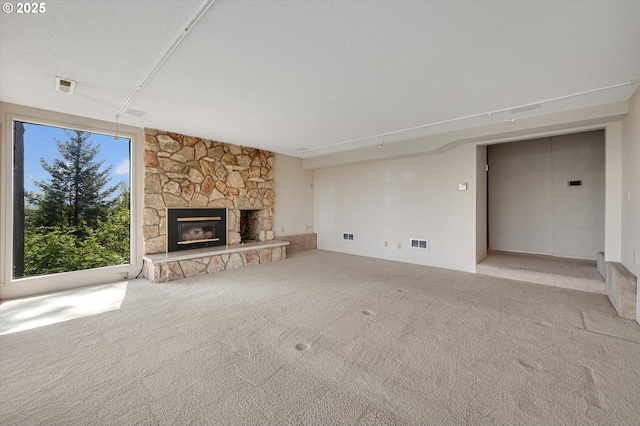 unfurnished living room with a stone fireplace and carpet