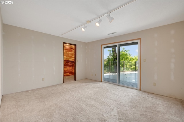 carpeted empty room with track lighting