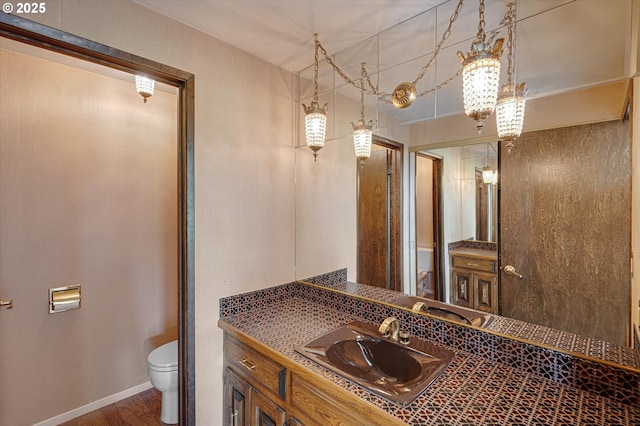 bathroom featuring toilet, baseboards, vanity, and wood finished floors