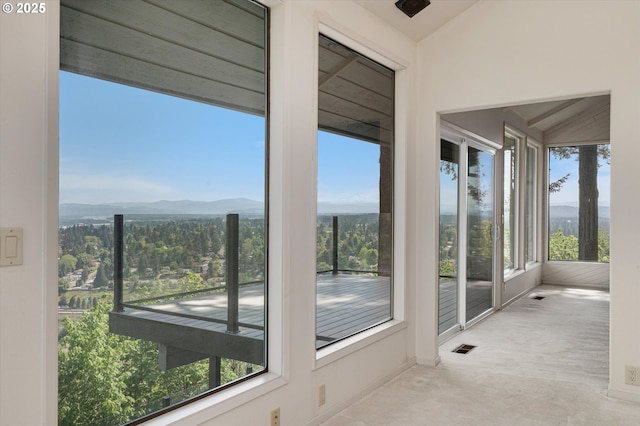unfurnished sunroom with a mountain view, carpet floors, and lofted ceiling