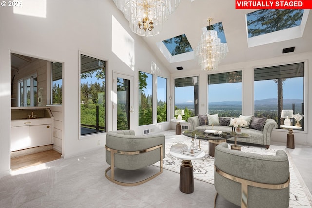sunroom / solarium with a chandelier, a skylight, and a high ceiling