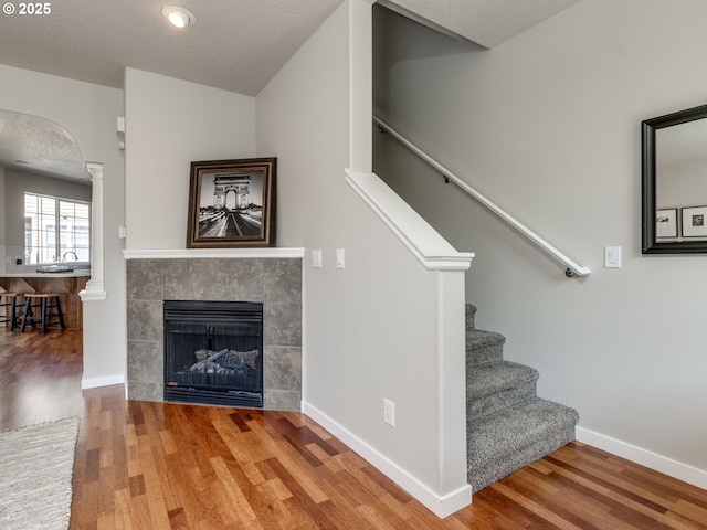 11656 SW Auklet Loop, Beaverton, OR 97007 - staircase featuring wood finished floors, a tile fireplace, decorative columns, and arched walkways