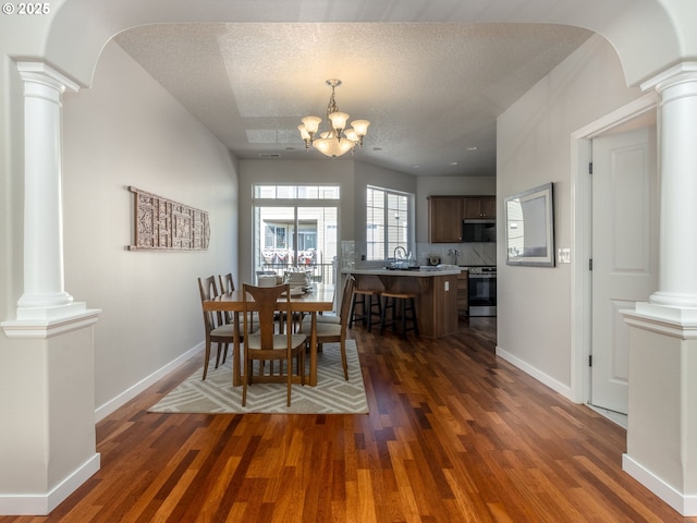 11656 SW Auklet Loop, Beaverton, OR 97007 - dining area with ornate columns, wood finished floors, a chandelier, and a textured ceiling