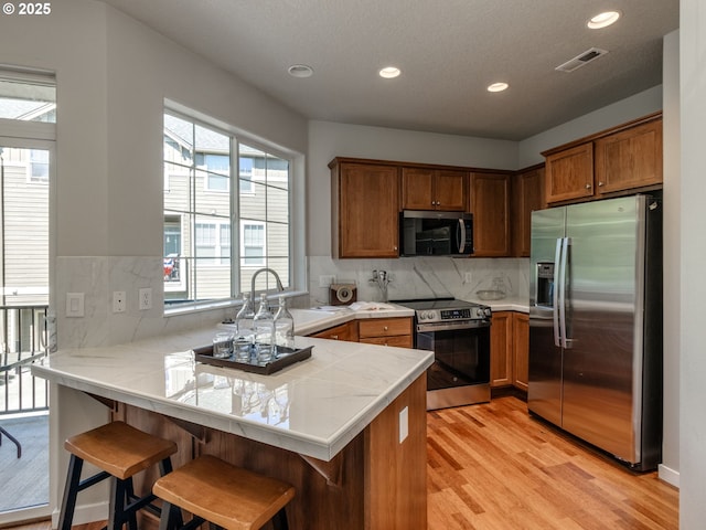 11656 SW Auklet Loop, Beaverton, OR 97007 - kitchen featuring stainless steel appliances, a peninsula, light wood finished floors, plenty of natural light, and recessed lighting
