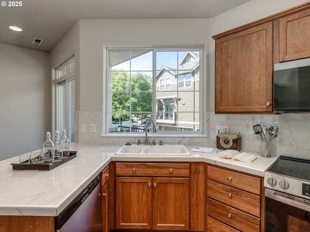 11656 SW Auklet Loop, Beaverton, OR 97007 - kitchen featuring appliances with stainless steel finishes, a peninsula, decorative backsplash, brown cabinets, and recessed lighting