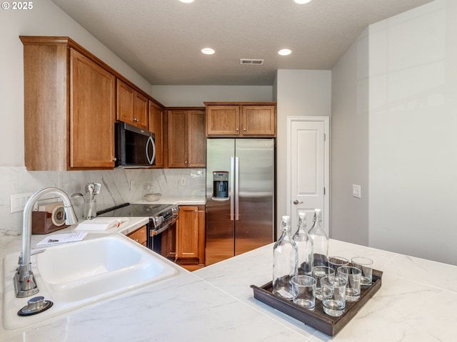 11656 SW Auklet Loop, Beaverton, OR 97007 - kitchen featuring stainless steel appliances, light countertops, brown cabinetry, recessed lighting, and tasteful backsplash