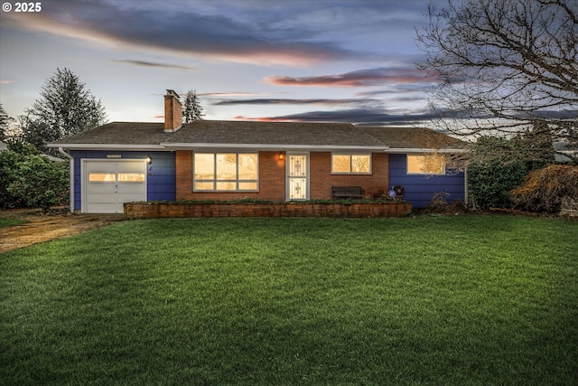 ranch-style home featuring a garage and a lawn