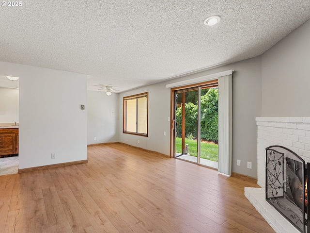 619 SE 121st Ave Unit 23, Vancouver, WA 98683 - unfurnished living room featuring a textured ceiling, a fireplace, light wood-style floors, a ceiling fan, and a sink