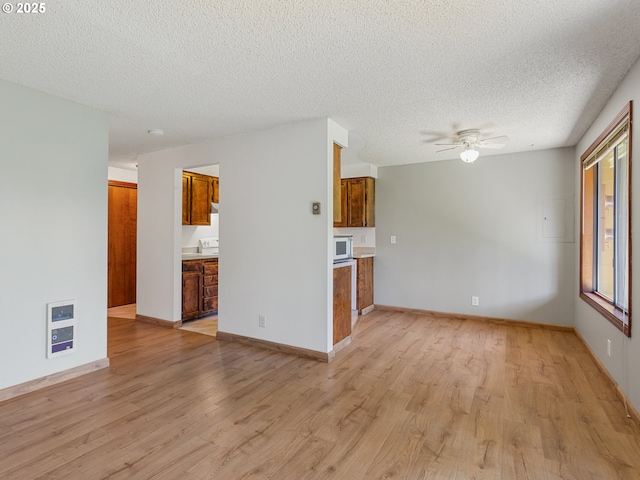 619 SE 121st Ave Unit 23, Vancouver, WA 98683 - unfurnished living room featuring light wood-type flooring, a textured ceiling, heating unit, a ceiling fan, and baseboards
