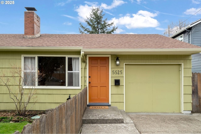 exterior space featuring an attached garage, a chimney, roof with shingles, and concrete driveway