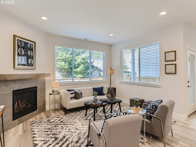 living room with recessed lighting, a tiled fireplace, and wood finished floors