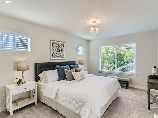 bedroom featuring light carpet and a notable chandelier